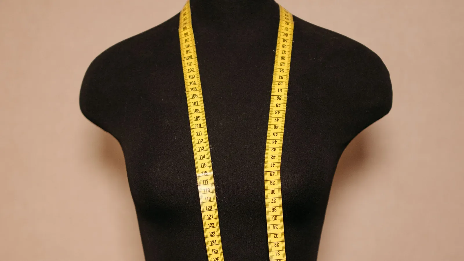 A black dressmaker's mannequin with a yellow tape measure draped around its neck