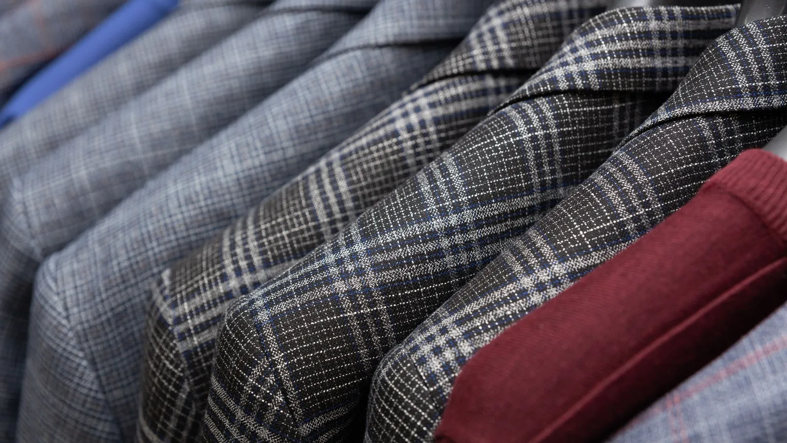Close-up of checked men's suit jackets hanging side by side on a rail