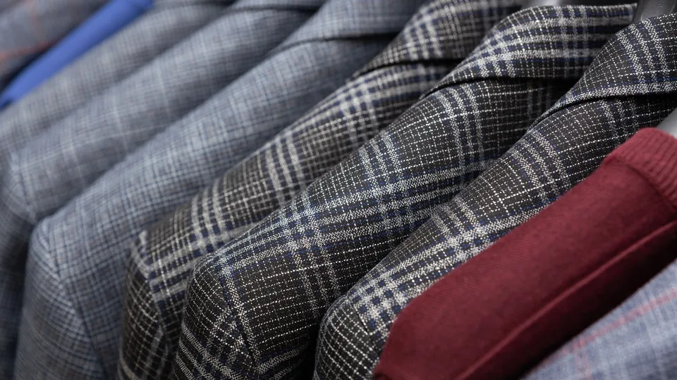 Close-up of checked men's suit jackets hanging side by side on a rail